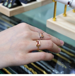 Detailed view of champagne rectangle zircon rings in gold and silver on a finger