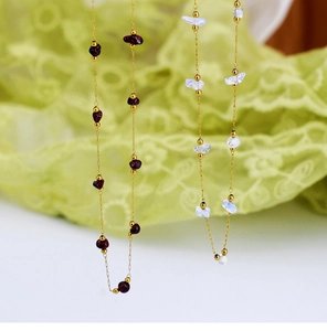 Detailed macro view of 18K gold-plated chains with irregular garnet and moonstone beads