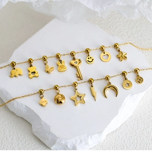 Detailed view of gold stainless steel bracelets with elephant and diamond key charms
