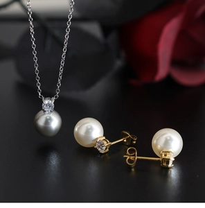 Detailed view of grey pearl pendant necklace and white pearl earrings with zircons