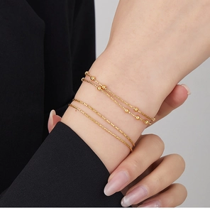 Detail of layered double snake chain bracelet with gold beads on model's wrist
