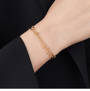 Close-up of double-layered snake chain bracelet with gold beads on a black suit background