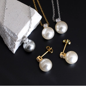 Macro view of grey pearl pendants and studs on stone over a dark background