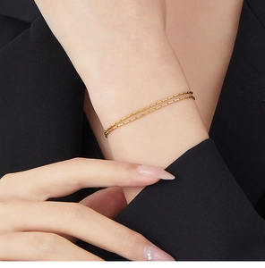 Close-up of double-layer gold snake chain bracelet worn on a female wrist over a black sleeve