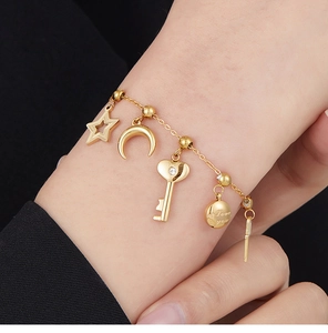 Detailed macro view of a gold-toned chain bracelet with star moon heart and Love You charms