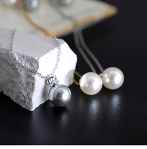 Macro shot of gray pearl pendant with sparkling stone on a delicate gold titanium chain