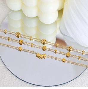 Detail of 18K gold-plated bracelets featuring star and heart motifs on a silk fabric