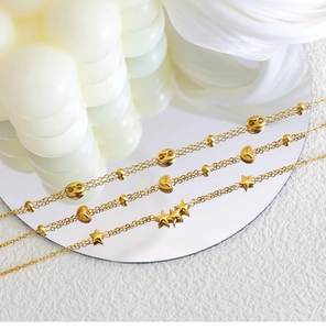 Detail view of 18K gold plated layered bracelets with star, heart and bean charms