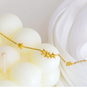 Detailed macro view of refined 18K gold plated bracelet featuring matte star pendants