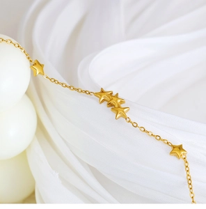 Close-up of 18K gold plated bracelet featuring solid star charms on silk background