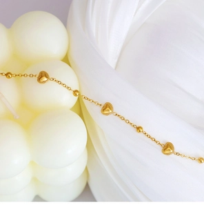 Detailed macro view of 18K gold plated heart pendant bracelet with micro-bead edges