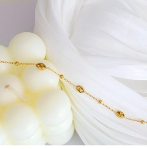Detail of 18K gold plated pig nose link bracelet on soft white silk with bubble candle