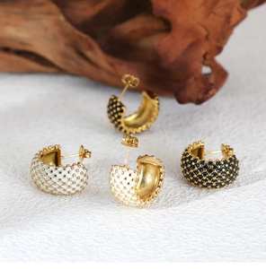 Detailed view of C-shaped gold plated earrings with textured black and white dots