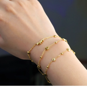 Close-up of 18K gold plated layered bracelets with star and heart charms on model wrist
