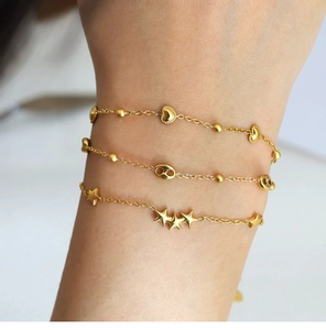 Macro view of three gold-plated titanium steel bracelets with star and heart charms