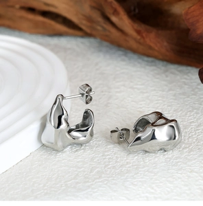 Detailed macro view of silver irregular lava-style earrings on minimalist display
