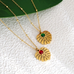 Tropical monstera leaf pendant necklace with red and green gems on golden bead chain