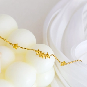 Minimalist 18K gold-plated star charm bracelet on elegant white fabric background