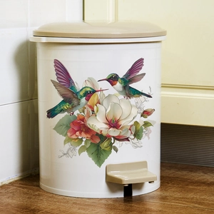 White pedal kitchen bin with colorful hummingbird flower pattern on wood floor
