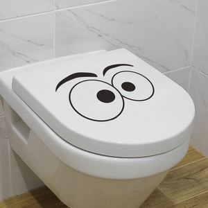 Funny cartoon eyes vinyl sticker on a white toilet lid in a modern bathroom decor