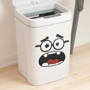 Smart white motion sensor trash can with cartoon face sticker on light wood floor