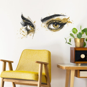 Sticker mural artistique yeux dorés pour salon au-dessus d'un fauteuil jaune