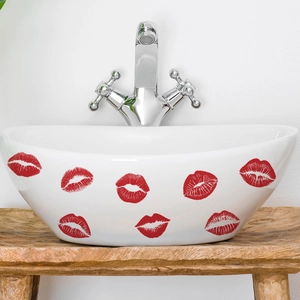 Semi-oval white ceramic washbasin with red lip patterns on a wooden countertop