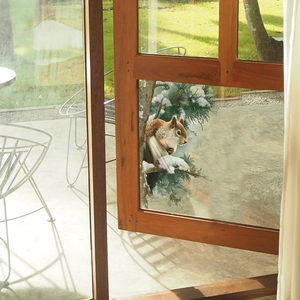 Translucent window sticker featuring a red squirrel on a snow-covered cedar branch