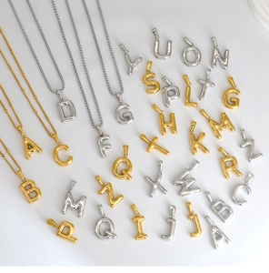 Detailed macro view of 3D polished 18K gold bubble letter pendants on ball chains