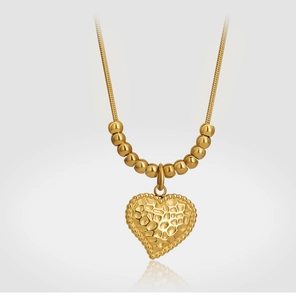 Dettaglio del ciondolo a cuore vintage con trama martellata e catena a serpente