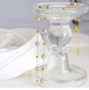 Details einer eleganten Goldkette mit Champagnerperlen und facettierten Metallperlen