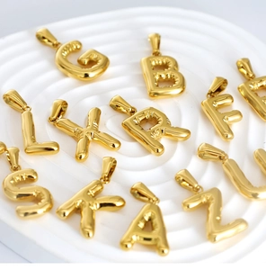 Detail of 18K gold-plated balloon letter pendants showing polished finish and textures