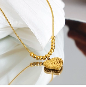 Dettaglio macro del ciondolo a cuore martellato vintage con perline e catena a serpente