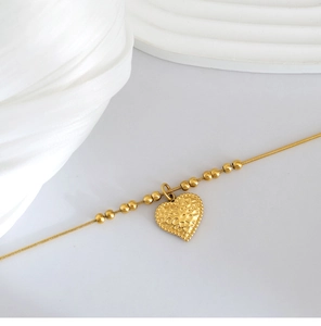 Dettaglio macro del ciondolo a cuore vintage placcato oro 18K con finitura martellata