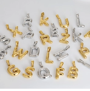 Macro detail of 3D bubble letter pendants in polished gold and silver finishes