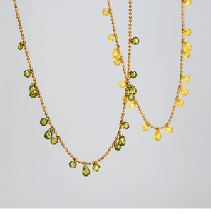 Close-up of teardrop olive green and yellow faceted crystals on gold beaded necklaces