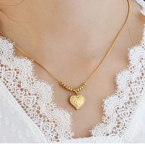 Dettaglio di una collana vintage a cuore con perline dorate e finitura martellata