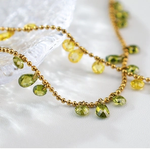 Macro shot of irregular teardrop green and yellow crystals on a gold beaded chain