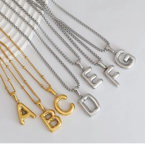 Detailed view of 3D balloon style letter pendants in polished gold and silver finishes