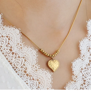 Dettaglio macro del ciondolo a cuore martellato dorato su collana a serpente