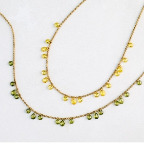 Macro shot of gold beaded necklace with faceted yellow and olive green teardrop gems