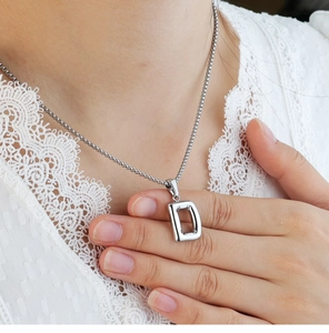 Detailed macro shot of a polished silver bubble letter D pendant on a beaded chain