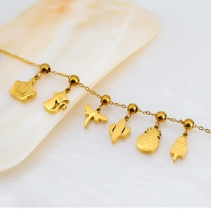 Polished gold-plated bracelet featuring charms of crown, cat, dragonfly, and pineapple