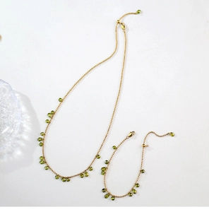 Detail view of gold bead necklace and bracelet set with olive green teardrop gemstones