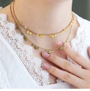 Detail view of double-layer beaded necklace with green and yellow teardrop crystals