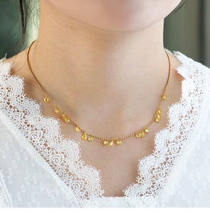 Close-up of golden beaded necklace with teardrop yellow gemstones worn on neck