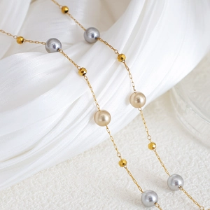 Elegante Goldkette mit grauen und champagnerfarbenen Perlen auf weißer Seide