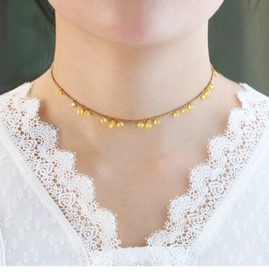 Close-up of a gold choker featuring irregular teardrop yellow crystals on a delicate chain