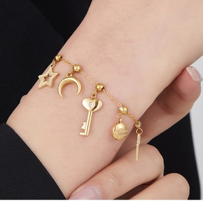 Close-up of gold chain bracelet featuring star, moon, and Love you engraved charms