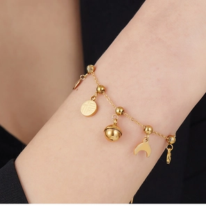 Detailed shot of golden charm bracelet with bell, moon, and Chinese fortune coin
